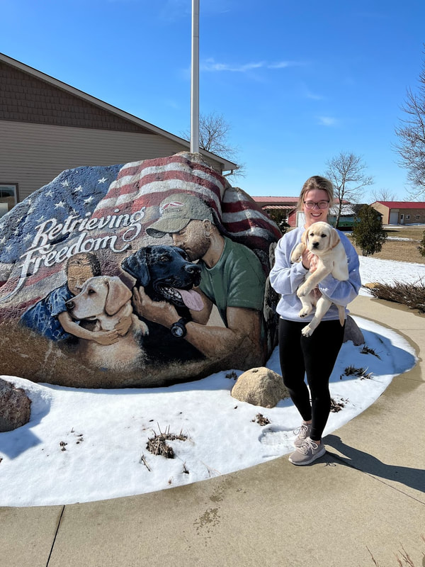 woman holding puppy by Retrieving Freedom sign